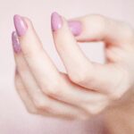 A close-up of a woman's hand showing a stylish pink and glittery manicure.